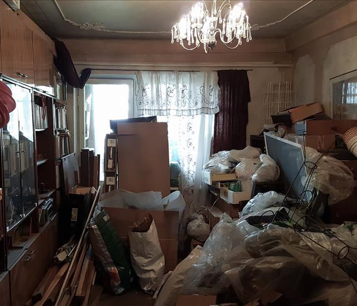 A room with a whole wall of built ins have loads of belongings including wood, boxes, plastic, bags, lamp shades and more