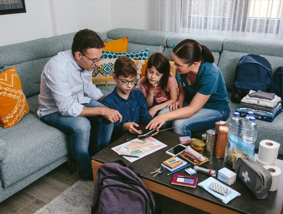 A family with young children sit together to plan for potential emergencies, exit plans, go-bags and to take safety measures