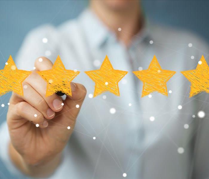A closeup of a customer filling in an online review and leaving five gold stars representing the highest satisfaction rating 