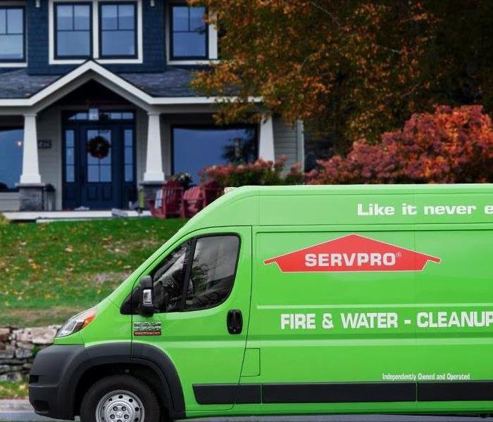 A distinguished home with a bright green SERVPRO van parked in front. Evidently servicing damages do to fire, water, or mold