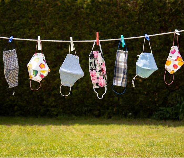 A clothing line is strung across a sunny spot in the yard. Washable face masks hang drying in the fresh air