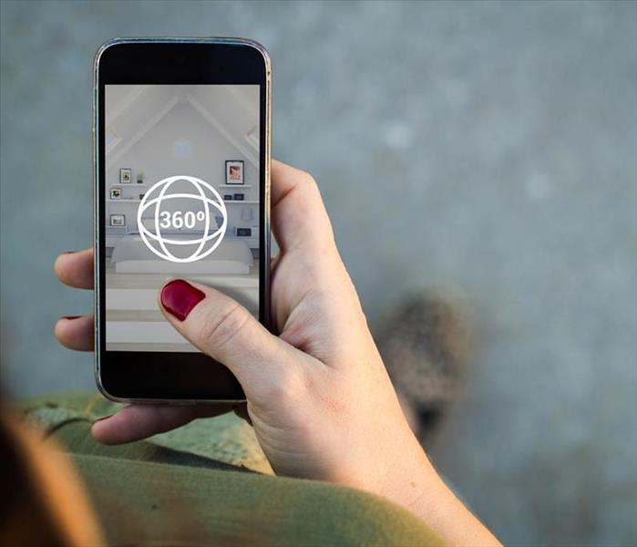 A woman holds her cell phone up to access a 360* scan & view feature for creating a virtual tour experience