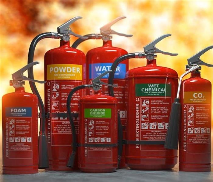 Flames are all a blaze in the back but 6 fire extinguishers are labeled according to use based on type of flames