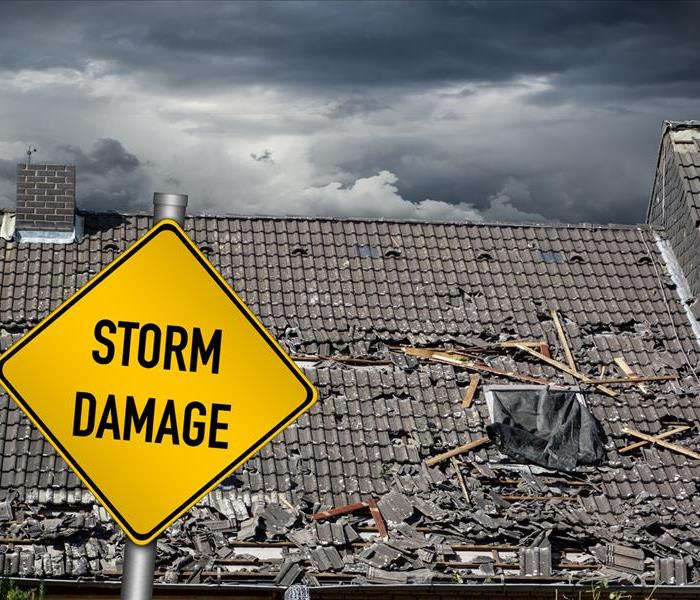 A storm damage warning as a stormy grey sky hovers over a storm damaged roof where debris has affected its integrity