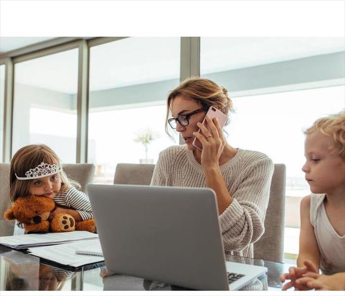A mom sitting at home in front of laptop with two toddlers is on a call. Maybe asking for help due to water damages...